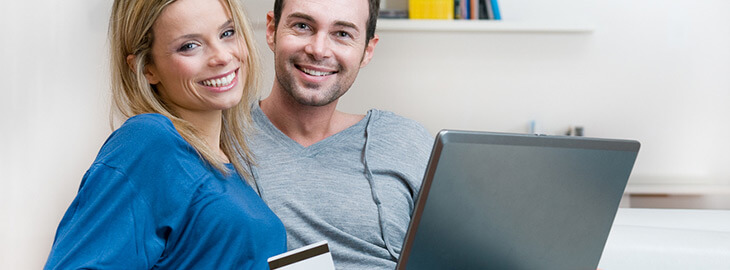 smiling couple holding credit card and laptop