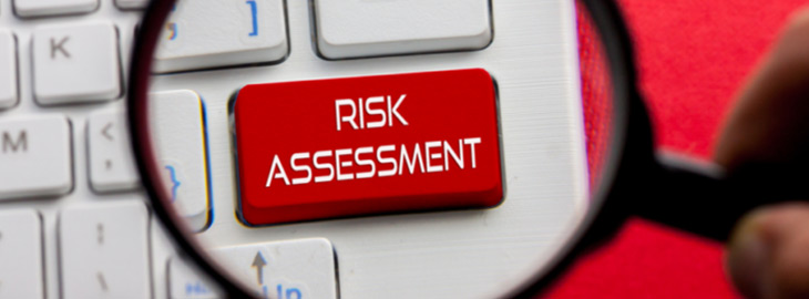 magnifying glass focusing on Risk Assessment button on computer keyboard