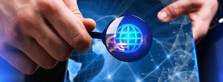 hand holding magnifying glass over spherical wireframe icon on digital screen