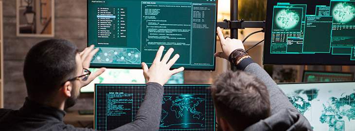 tech engineers pointing at code on a computer screen
