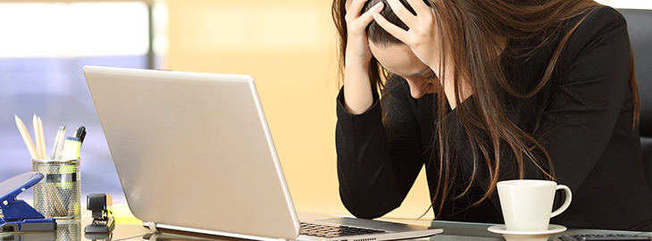 businesswoman looking at her laptop while holding her head in desperation