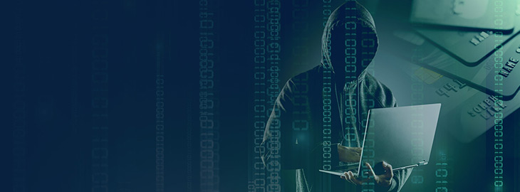 binary code and credit cards overlaying a hooded hacker holding a laptop